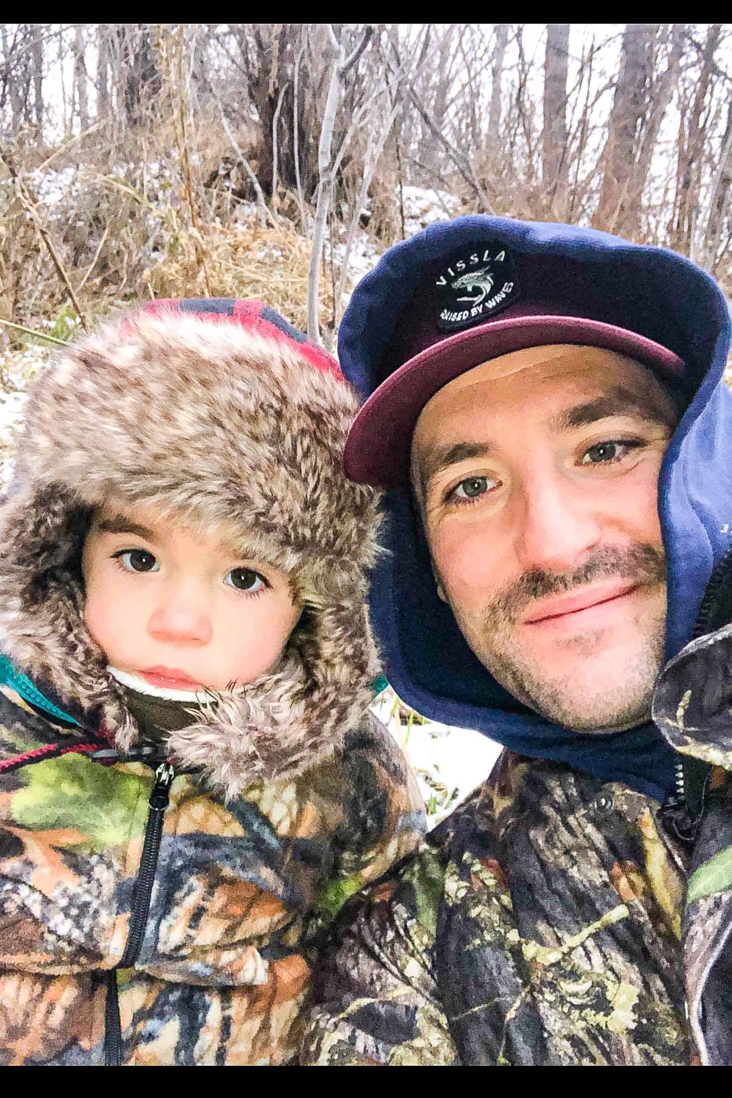 A father and son in hunting clothes in the snowy forest.