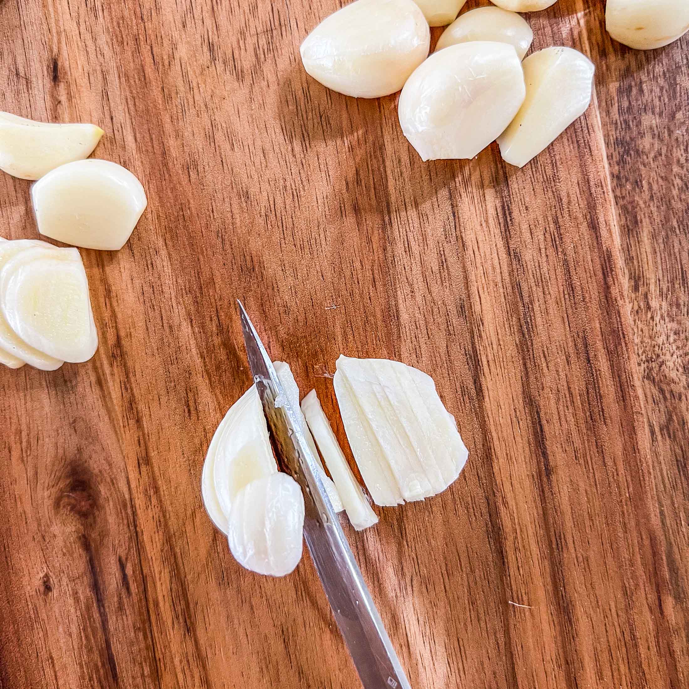Finely cutting a clove of peeled garlic.