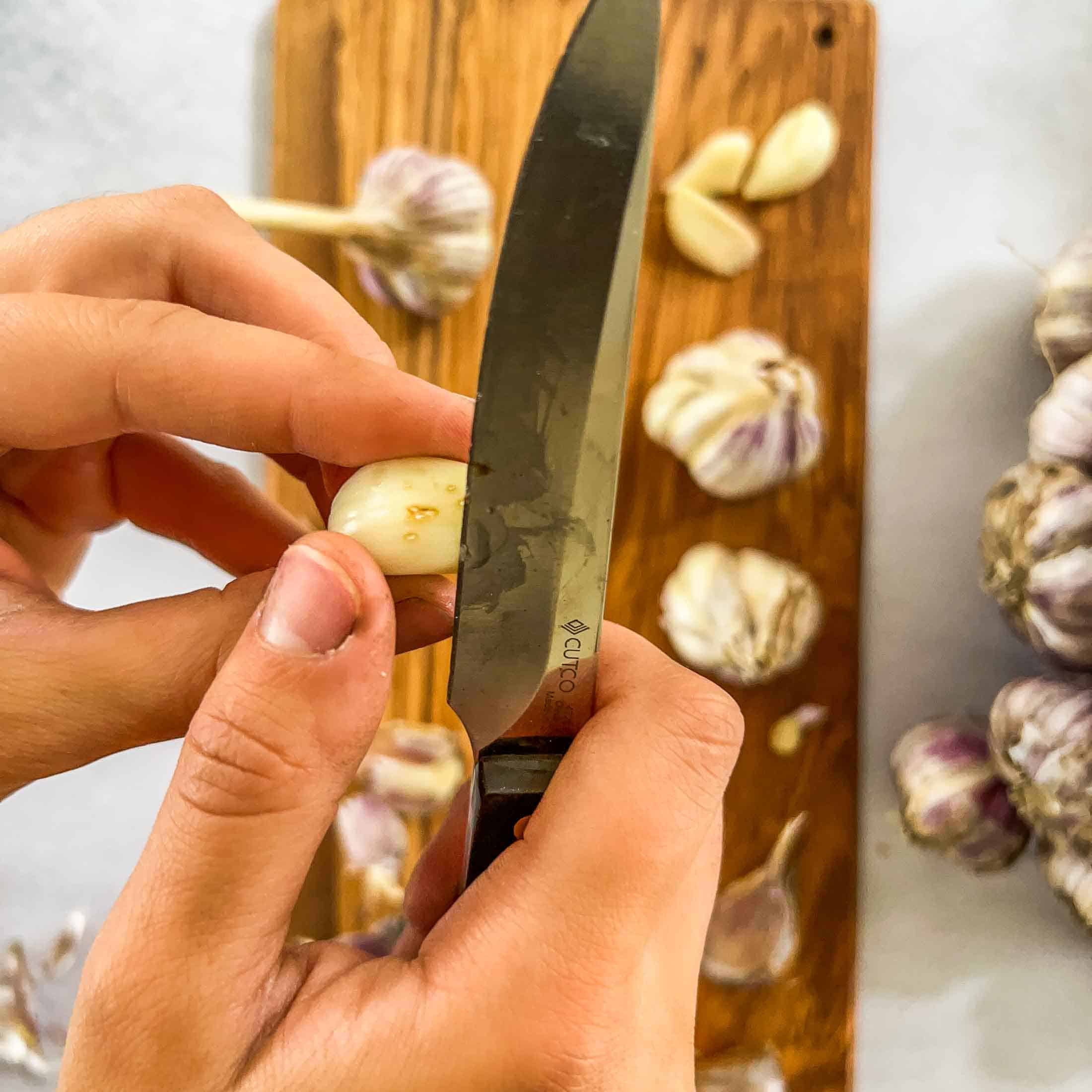 Slicing the blemishes off of a clove of garlic.