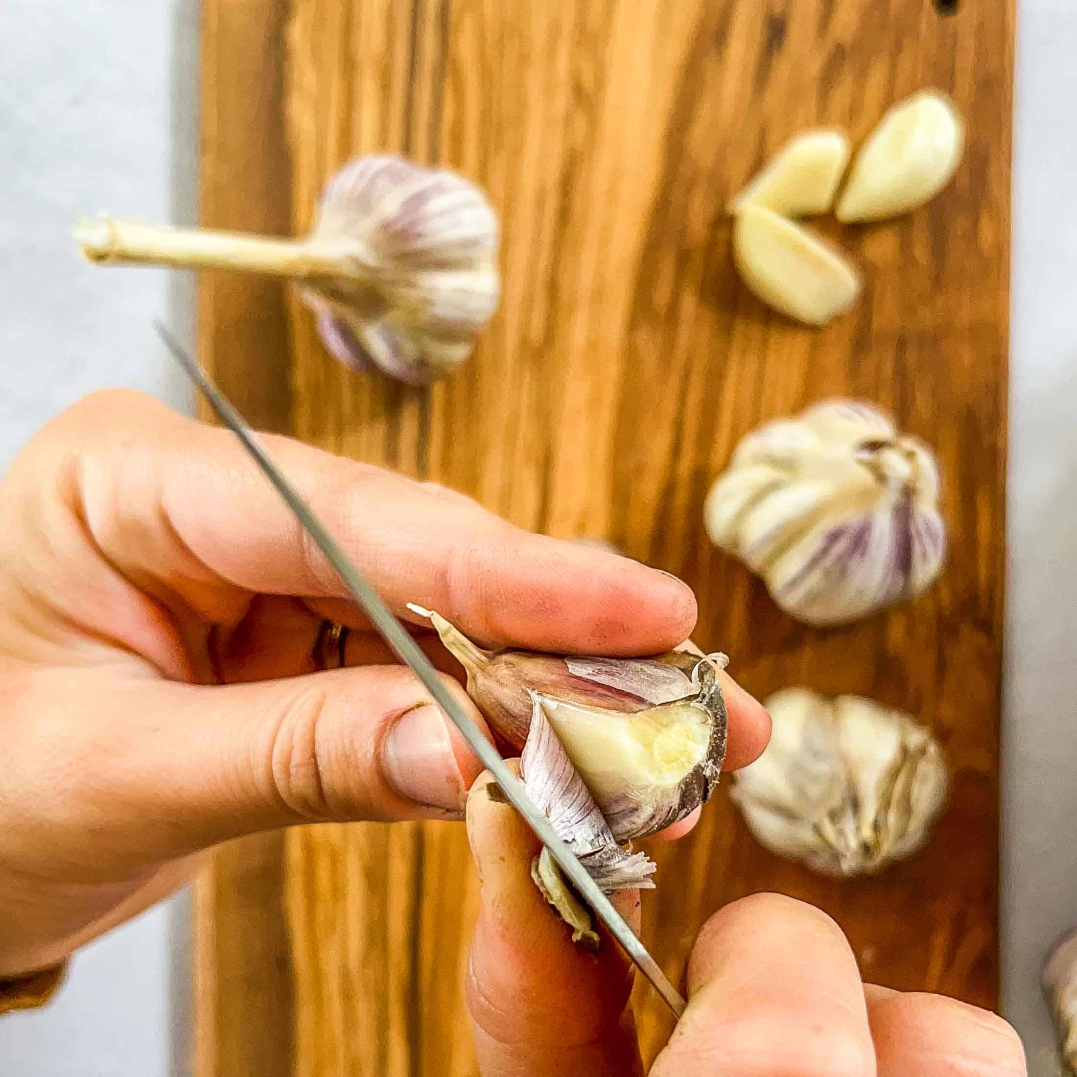 Peeling the outer peel off of a clove of garlic with a knife.