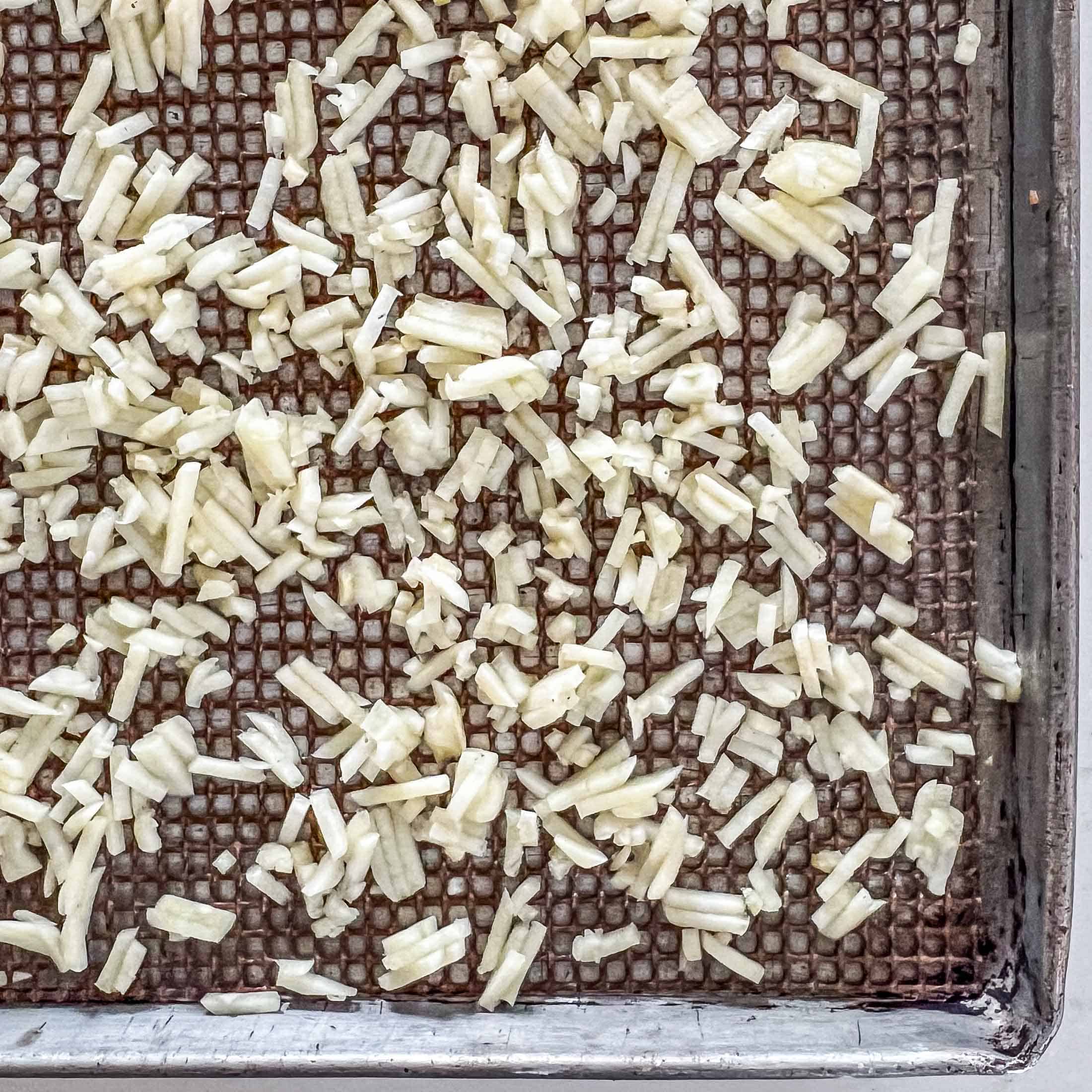 Minced garlic on a baking sheet before drying.