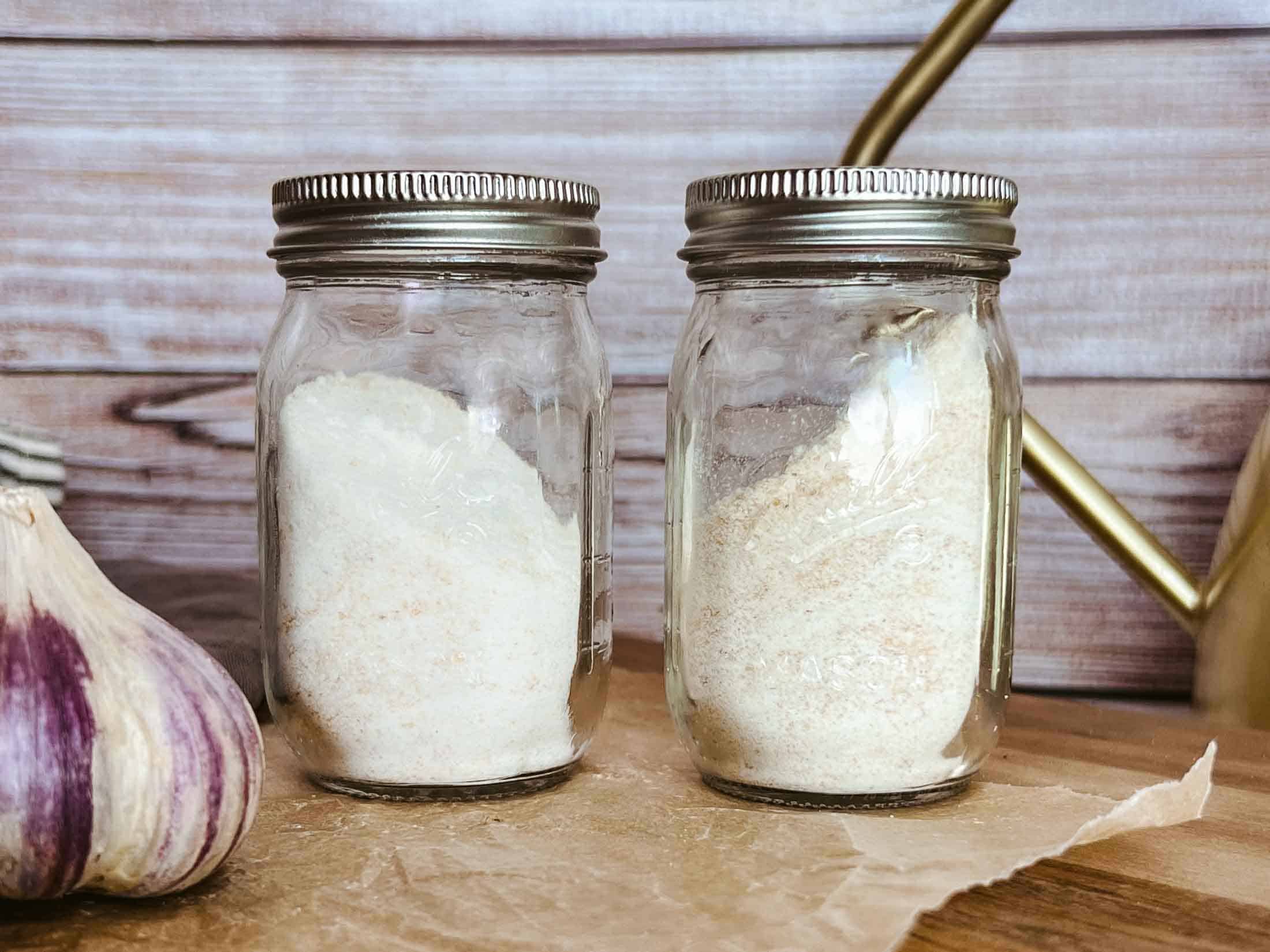 Homemade garlic powder and garlic salt in glass spice jars.