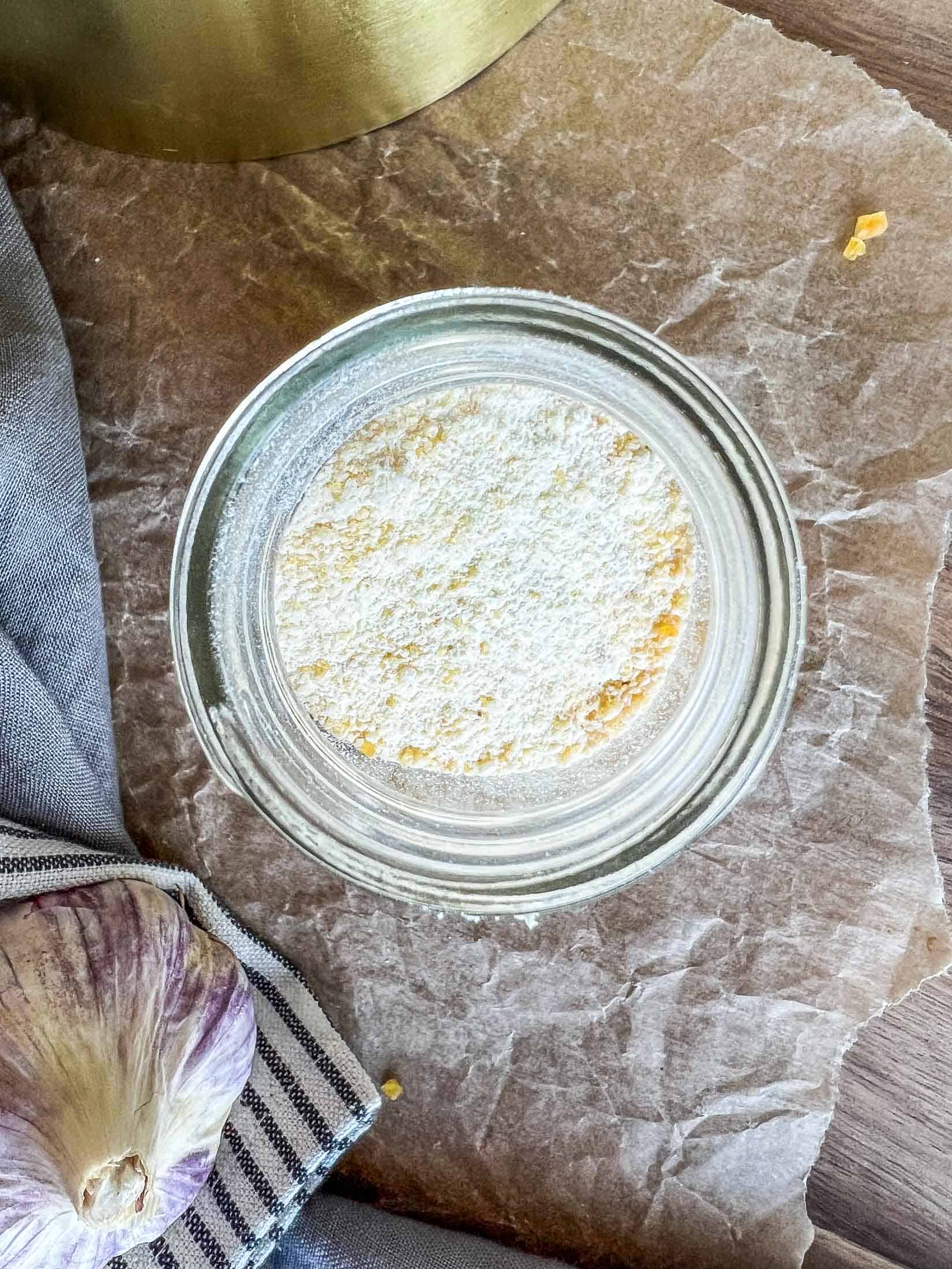 Homemade dried garlic powder in a glass spice jar.