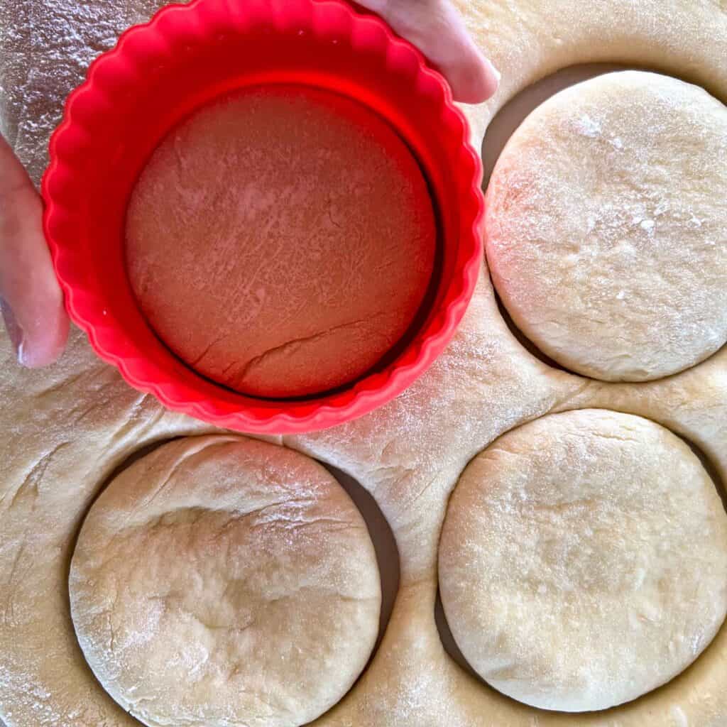 English muffins being cut out using a 3 inch diameter cutter.